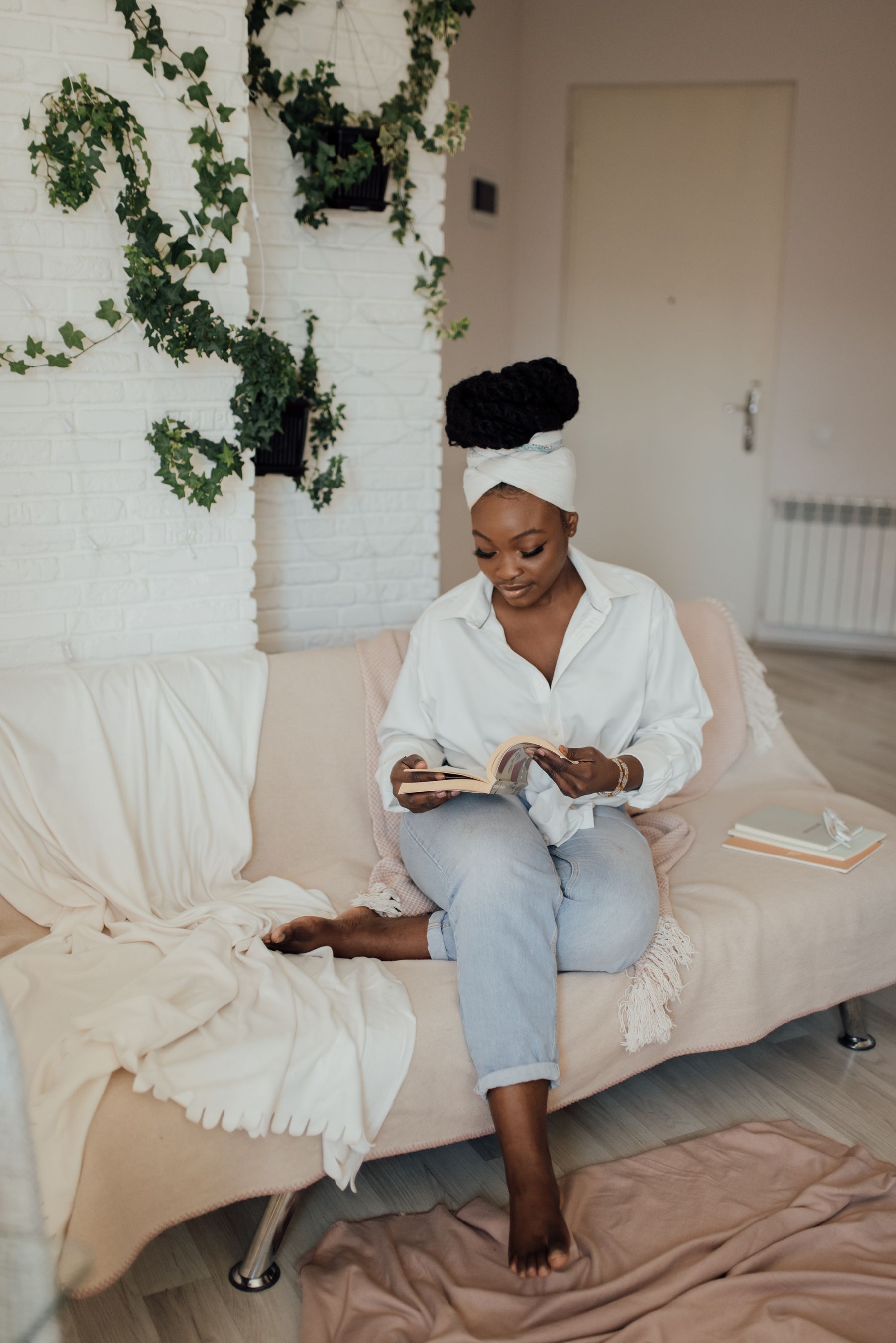 A woman reading a book on a sofa at home